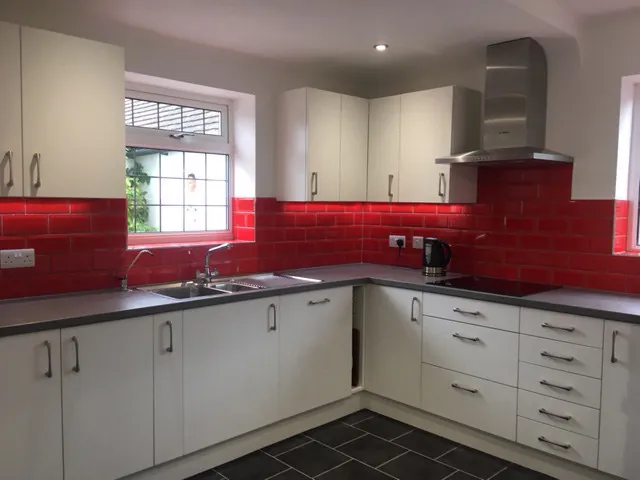 White kitchen with red metro tiles and a steel cooker hood
